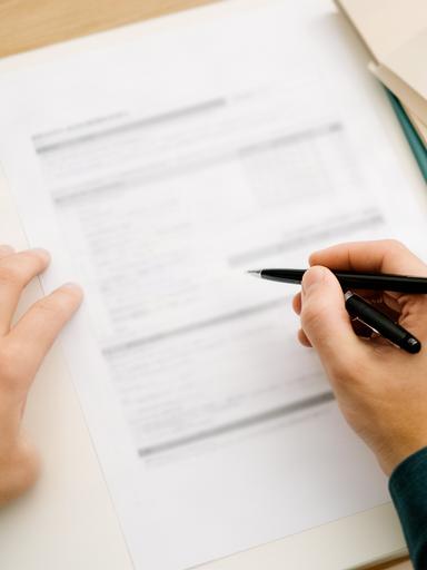 資産形成資料を見ながら内容を確認する手元とペン
